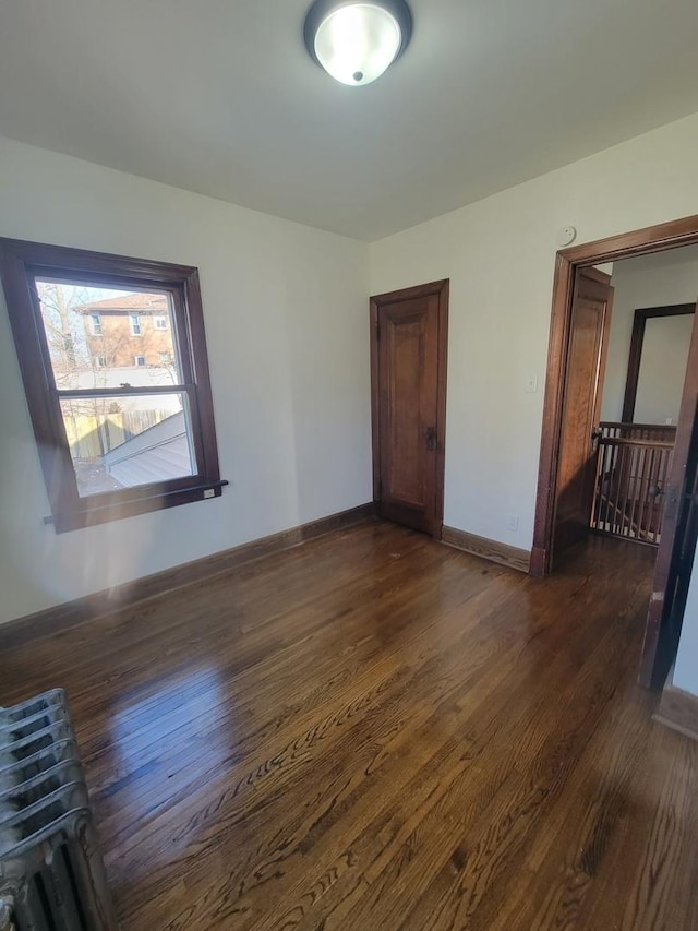 spare room with dark hardwood / wood-style flooring and radiator heating unit