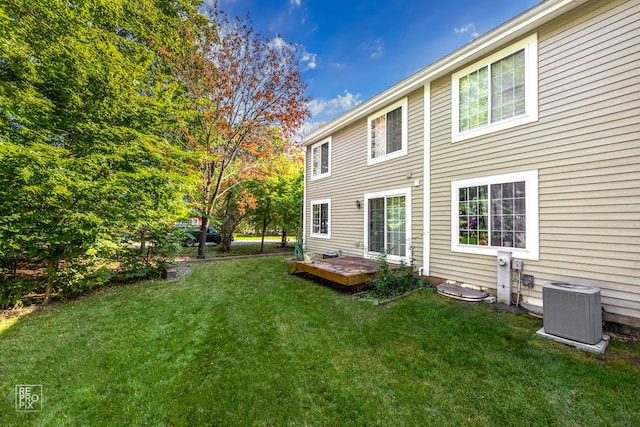 rear view of property featuring central AC and a lawn