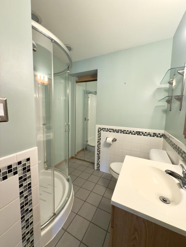 bathroom with tile patterned flooring, toilet, vanity, and a shower with shower door