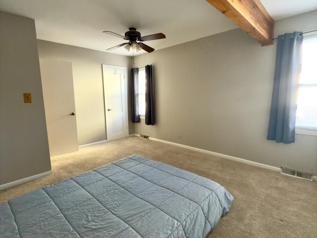 bedroom featuring multiple windows, ceiling fan, light carpet, and beam ceiling