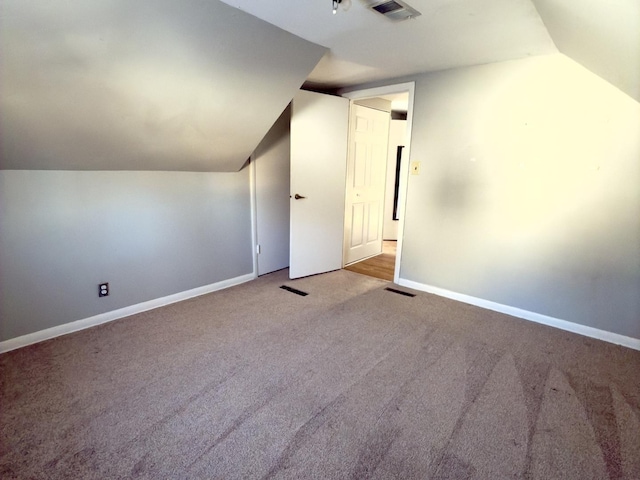 bonus room with lofted ceiling and light colored carpet