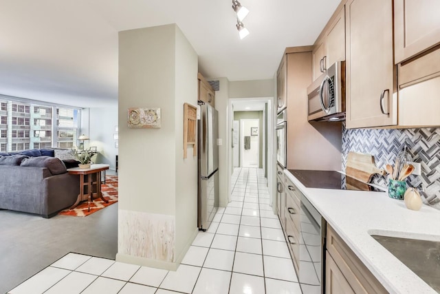 kitchen featuring light brown cabinets, stainless steel appliances, backsplash, light tile patterned flooring, and light stone counters