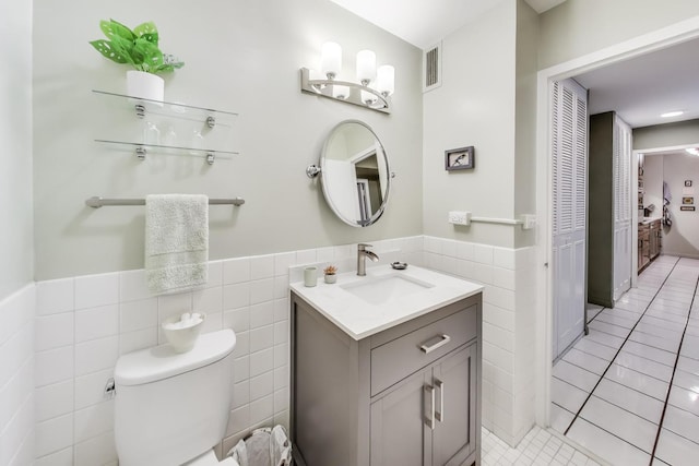 bathroom with vanity, toilet, tile walls, and tile patterned flooring