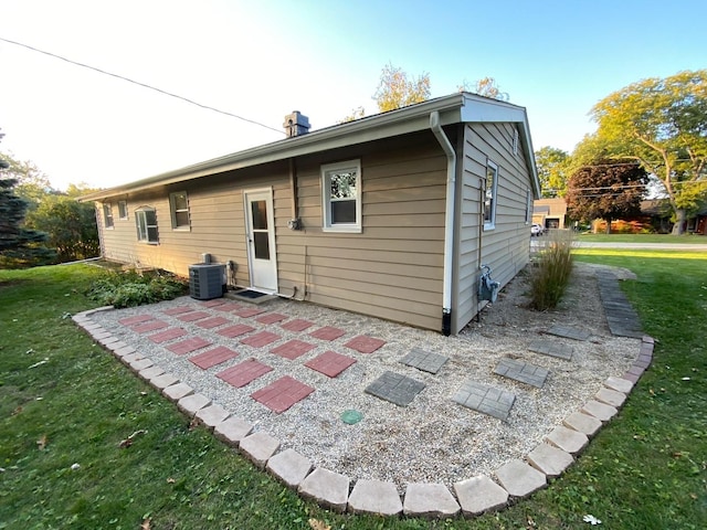 rear view of house with a patio area, central air condition unit, and a yard