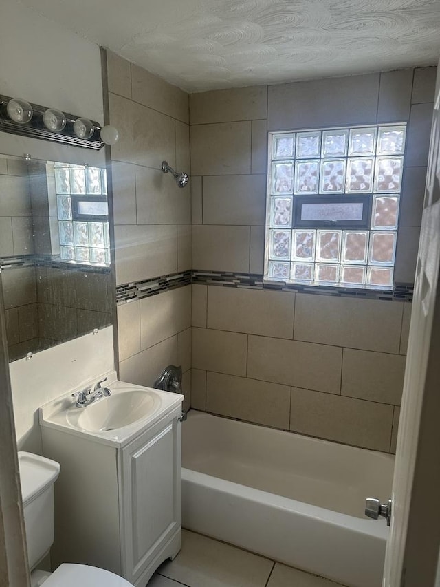 full bathroom featuring toilet, vanity, tile patterned flooring, and tiled shower / bath