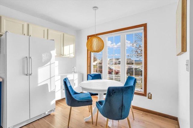 dining space with light wood-style flooring and baseboards