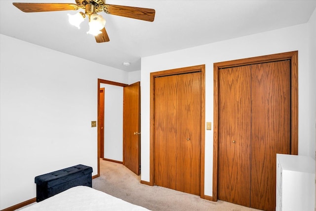 bedroom with multiple closets, carpet flooring, ceiling fan, and baseboards