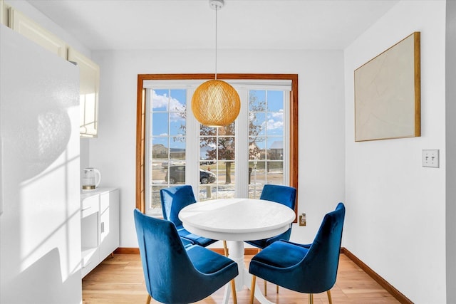 dining space featuring light wood finished floors and baseboards