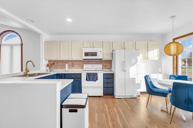 kitchen featuring white appliances, a sink, cream cabinetry, and blue cabinets