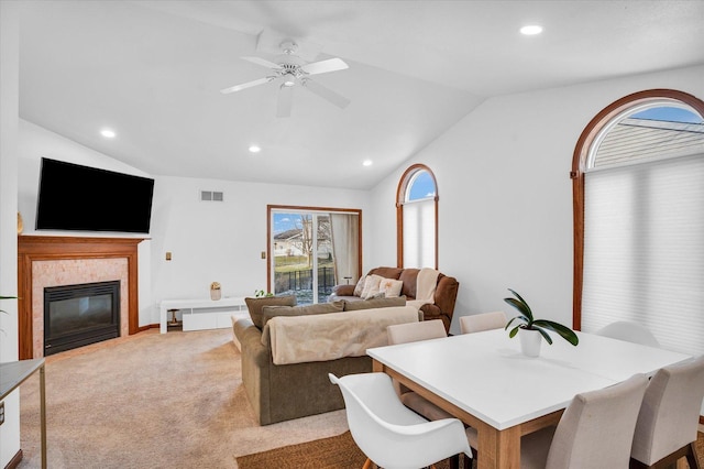 carpeted dining room with lofted ceiling, visible vents, a tiled fireplace, and recessed lighting