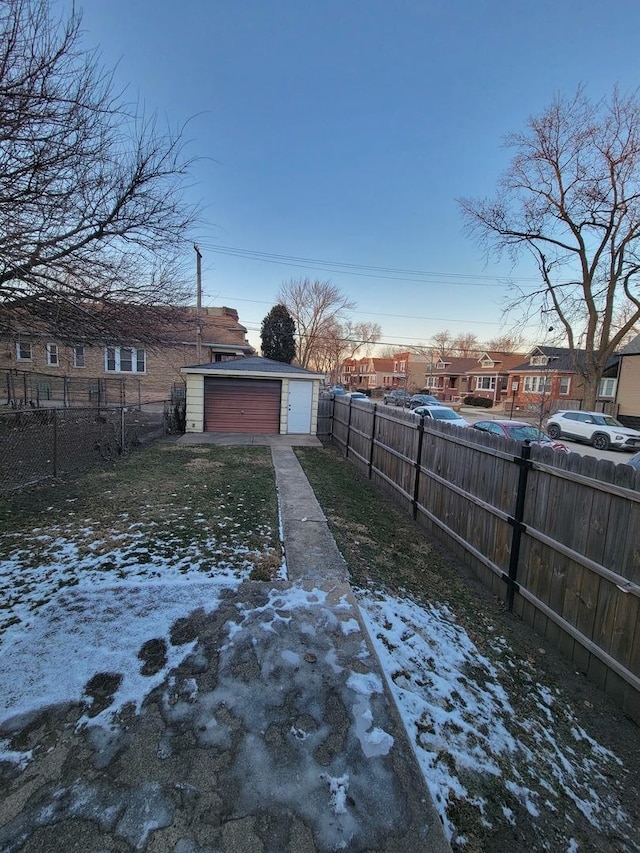 yard layered in snow with a garage and an outbuilding