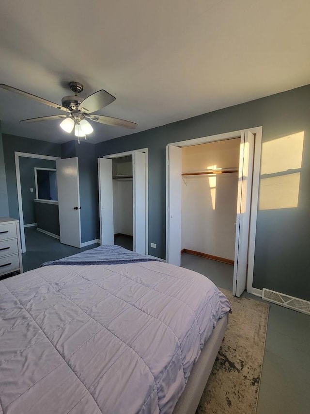 bedroom with ceiling fan and two closets