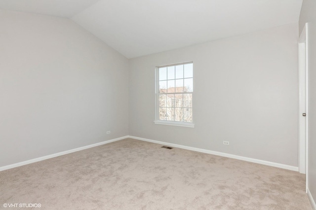 spare room featuring vaulted ceiling and light carpet