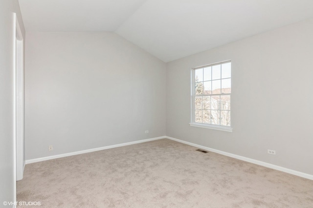 unfurnished room featuring vaulted ceiling and light carpet