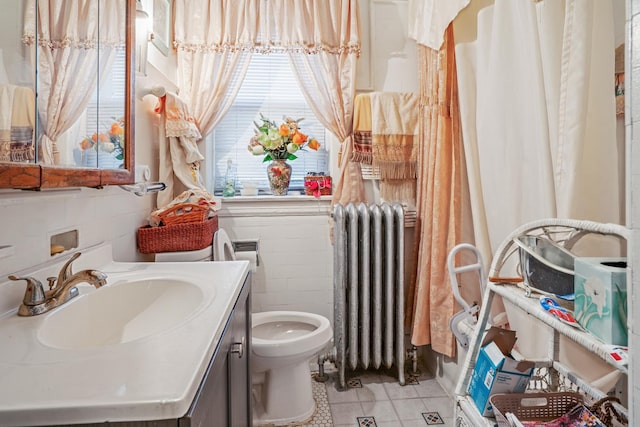 bathroom with tile patterned flooring, tile walls, radiator, toilet, and vanity