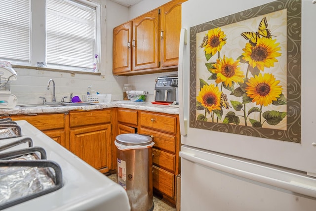 kitchen with sink, backsplash, white refrigerator, and stove