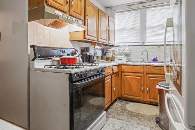 kitchen featuring fridge, backsplash, sink, and white gas range oven