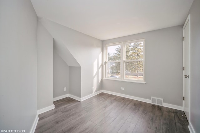 additional living space with wood finished floors, visible vents, and baseboards