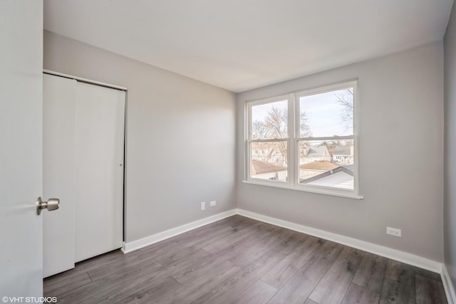 unfurnished bedroom with wood finished floors, baseboards, and a closet