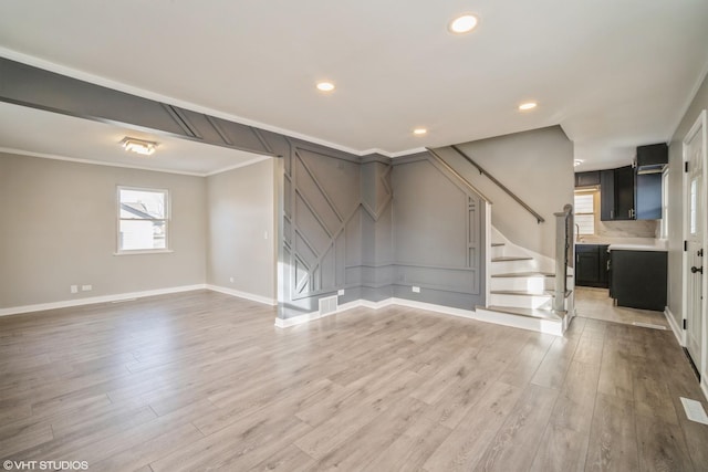 unfurnished living room with visible vents, ornamental molding, stairway, light wood finished floors, and baseboards