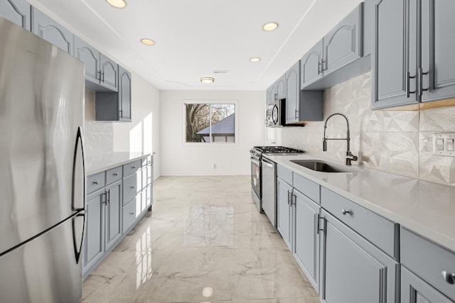 kitchen with tasteful backsplash, stainless steel appliances, sink, and gray cabinetry