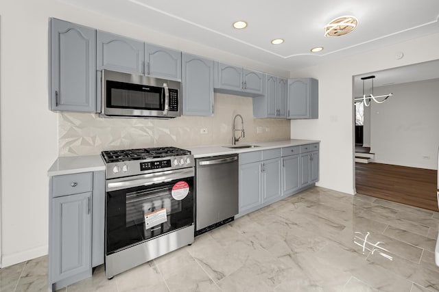 kitchen with sink, appliances with stainless steel finishes, gray cabinetry, backsplash, and hanging light fixtures