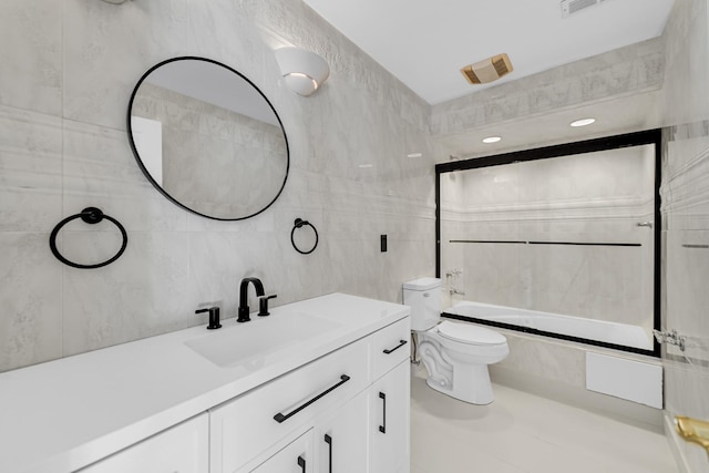 full bathroom featuring tiled shower / bath, vanity, toilet, and tile walls