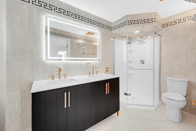 bathroom featuring tile walls, vanity, a shower with shower door, tile patterned floors, and toilet