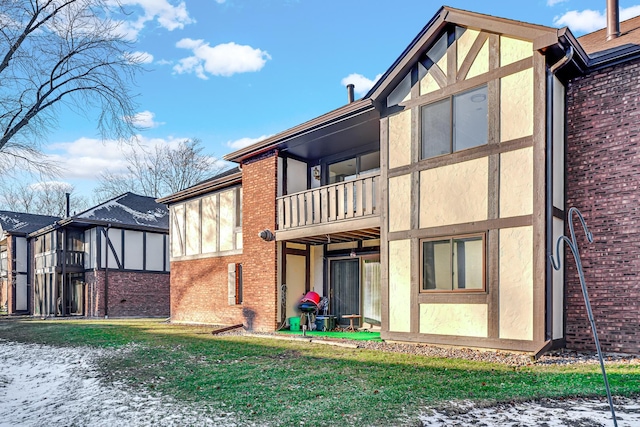 rear view of property with a balcony and a lawn