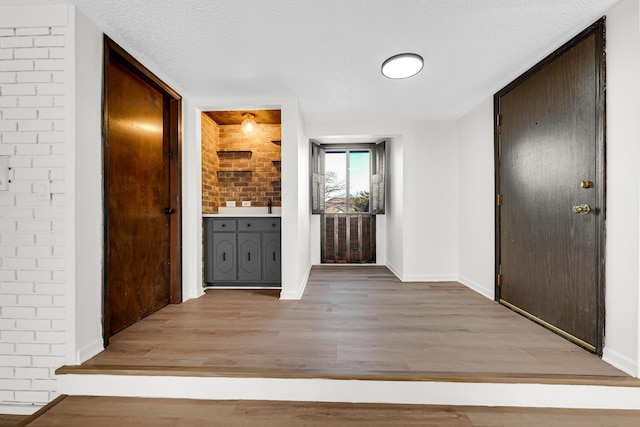 hallway with a textured ceiling and light wood-type flooring