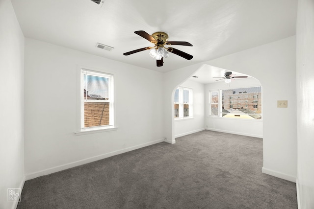 spare room with ceiling fan and dark colored carpet