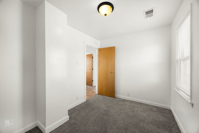 unfurnished room with dark carpet and a healthy amount of sunlight