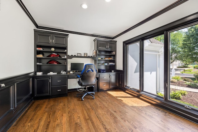 office space featuring a wainscoted wall, ornamental molding, dark wood-style flooring, and built in study area