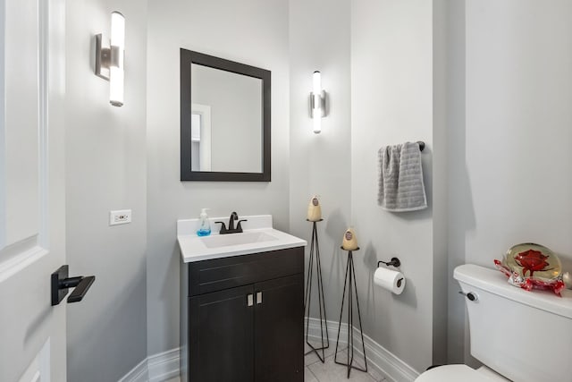 bathroom featuring vanity, toilet, baseboards, and tile patterned flooring