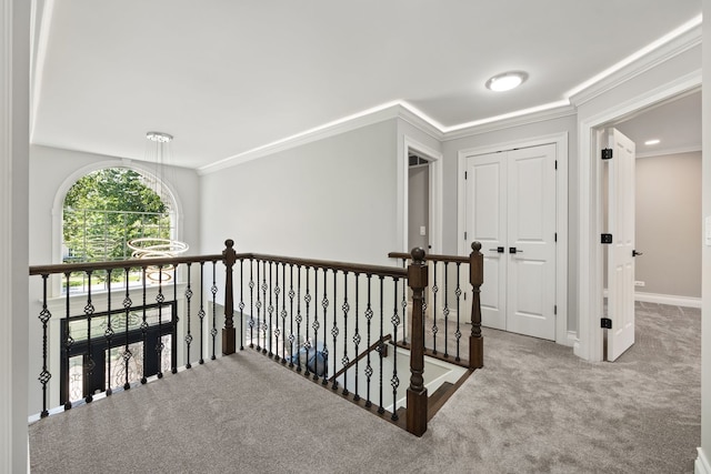 hallway with an upstairs landing, ornamental molding, baseboards, and carpet floors