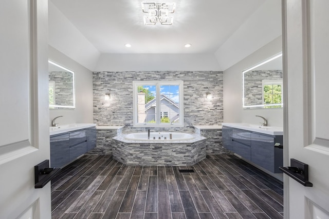 full bathroom with a sink, a garden tub, two vanities, and wood tiled floor