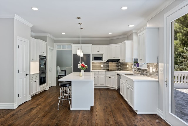 kitchen with a center island, dark wood-type flooring, stainless steel appliances, white cabinetry, and a sink