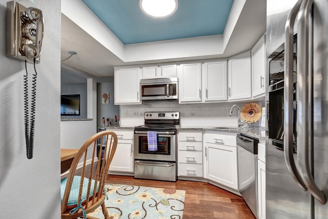 kitchen with stainless steel appliances, sink, white cabinets, and light wood-type flooring