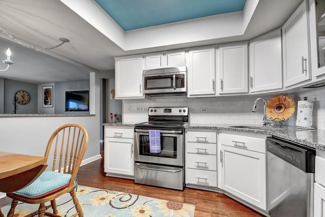 kitchen with white cabinetry, stainless steel appliances, and light stone countertops