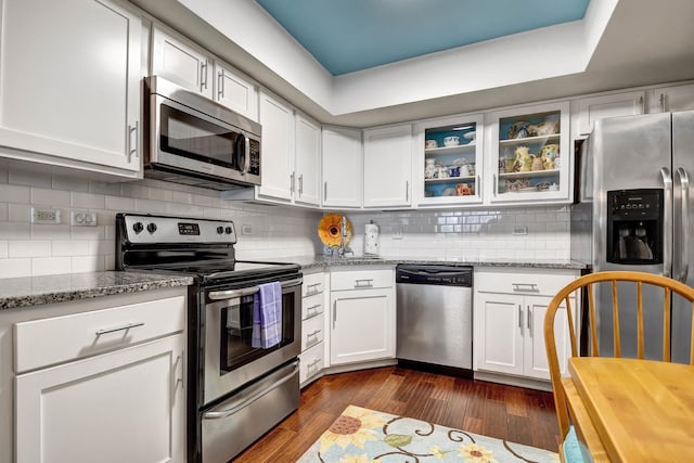 kitchen featuring white cabinetry, light stone counters, dark hardwood / wood-style floors, and appliances with stainless steel finishes