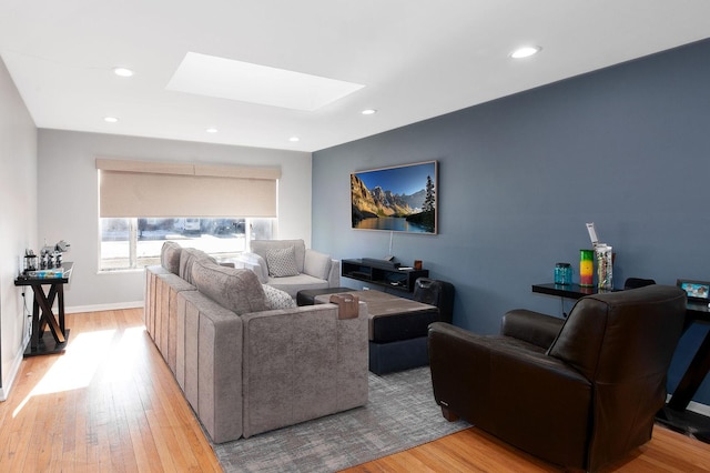 living room featuring a skylight and light hardwood / wood-style flooring