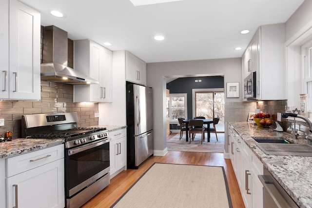 kitchen with white cabinetry, wall chimney exhaust hood, and stainless steel appliances