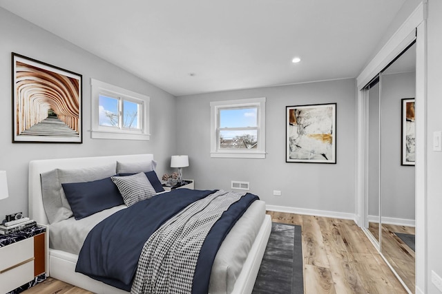 bedroom featuring multiple windows, light hardwood / wood-style flooring, and a closet