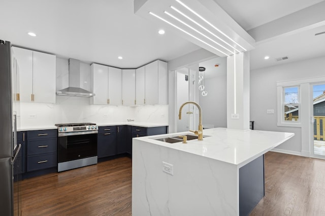 kitchen with a kitchen island with sink, wall chimney range hood, white cabinetry, and stainless steel appliances