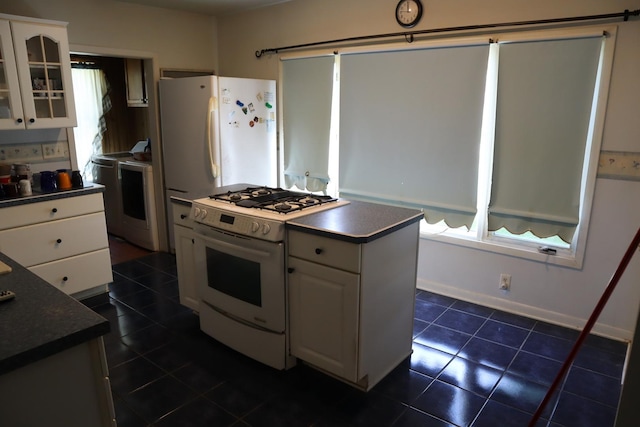 kitchen with white appliances, white cabinetry, and a kitchen island