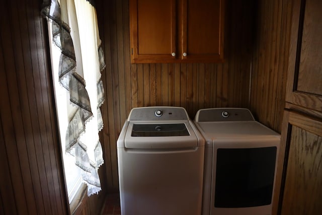 laundry area with cabinets, washer and clothes dryer, and wooden walls