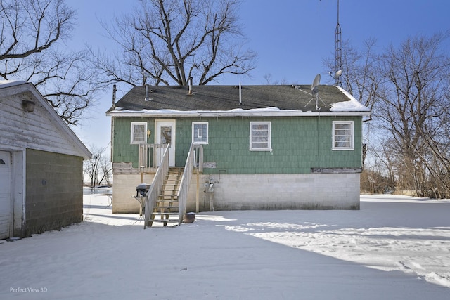 snow covered rear of property featuring a garage