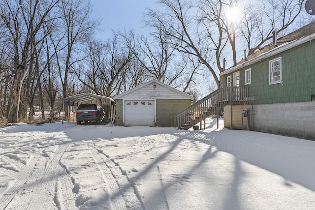 yard covered in snow with a garage, an outbuilding, and a carport