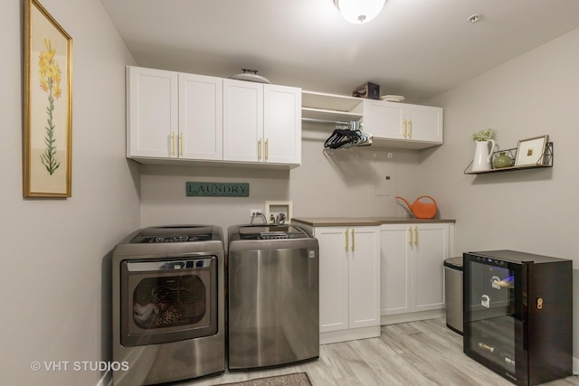 washroom featuring wine cooler, cabinets, washer and clothes dryer, and light hardwood / wood-style flooring