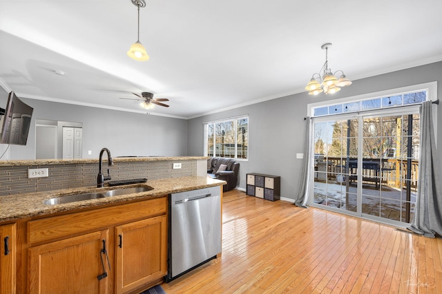 kitchen with sink, decorative light fixtures, light stone counters, and stainless steel dishwasher